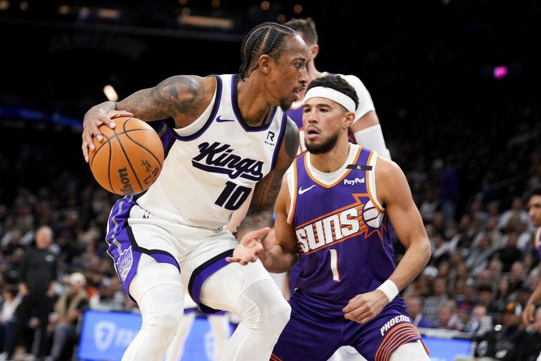 DeMar DeRozan (10), de los Kings de Sacramento, maneja el balón ante la presión defensiva de Devin Booker (1), de los Suns de Phoenix, durante la primera mitad del juego de baloncesto de la NBA, el domingo 10 de noviembre de 2024, en Phoenix. (AP Foto/Samantha Chow)