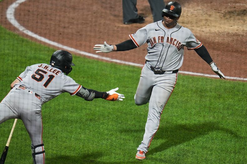 Rafael Devers, derecha, de los Gigantes de San Francisco, es felicitado por Jung Hoo Lee (51) después de anotar carrera con un elevado de sacrificio de Turner Hill ante el relevista de los Piratas de Pittsburgh, Camilo Doval, durante la 10ma entrada del juego de béisbol de Grandes Ligas, el miércoles 2 de septiembre de 2026, en Pittsburgh. (AP Foto/Gene J. Puskar)
