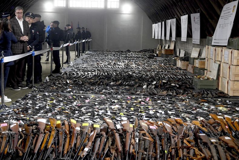 En esta imagen proporcionada por el Servicio de Prensa de la Presidencia Serbia, el presidente de Serbia, Aleksandar Vucic, a la izquierda, inspecciona armas reunidas como parte de una campaña de desarme cerca de la ciudad de Smederevo, Serbia, el domingo 14 de mayo de 2023. (Servicio de Prensa de la Presidencia Serbia via AP)