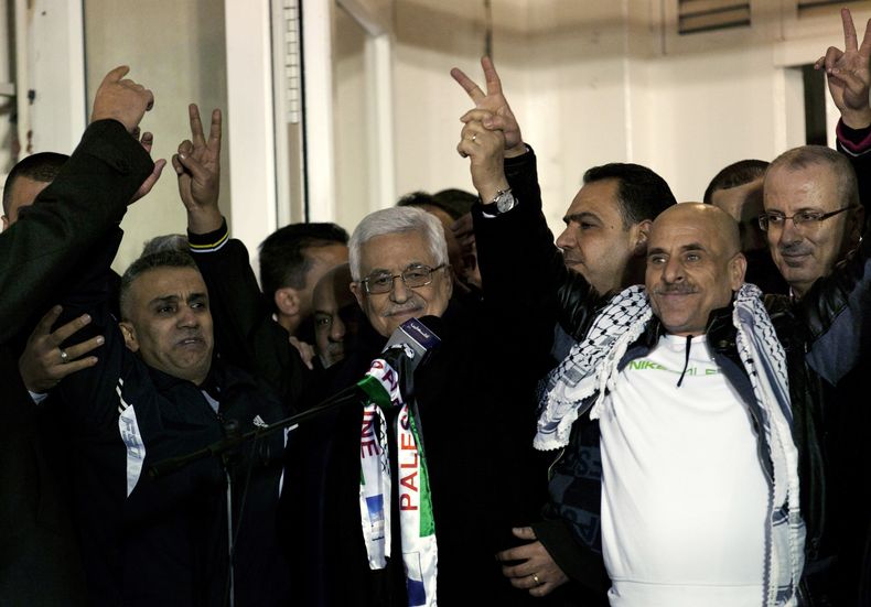 El presidente palestino Mahmud Abbas (centro) recibe a prisioneros palestinos liberados durante una ceremonia de bienvenida a su llegada a la sede del gobierno en la ciudad de Ramala, en Cisjordania, el martes 31 de diciembre de 2013. (Foto AP/Nasser Nass