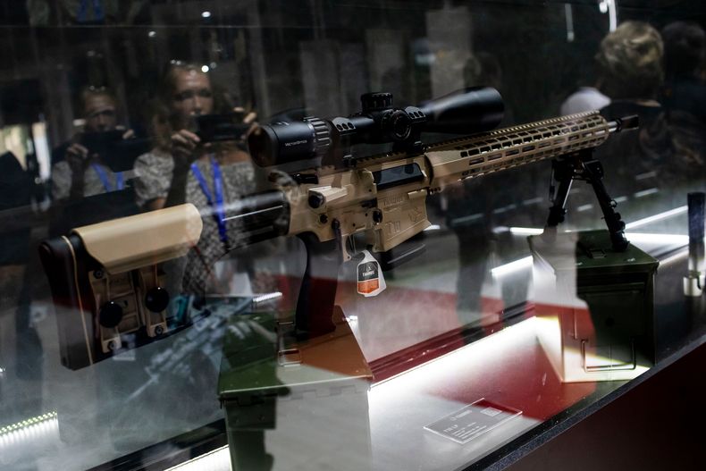 ARCHIVO - Reflejado en un vidrio, un visitante toma fotos de un rifle T10 LP exhibido en la Exposición Internacional de Defensa y Seguridad LAAD en Río de Janeiro, el 11 de abril de 2023. La exhibición de defensa y seguridad más grande de América Latina presenta armas, cámaras de seguridad, vehículos a prueba de balas y accesorios. (AP Foto/Bruna Prado, Archivo)
