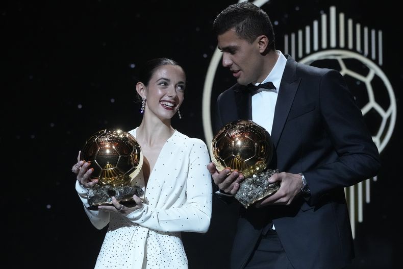 Los jugadores españoles Aitana Bonmatí (izquierda) y Rodri Hernández muestras sus trofeos al Balón de Oro, el lunes 28 de octubre de 2024, en París. (AP Foto/Michel Euler)