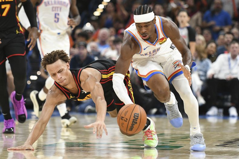 Shai Gilgeous-Alexander, derecha, del Thunder de Oklahoma City, intenta controlar un balón disputado con Dyson Daniels, izquierda, de los Hawks de Atlanta, durante la segunda mitad del juego de baloncesto de la NBA, el domingo 27 de octubre de 2024, en Oklahoma City. (AP Foto/Kyle Phillips)