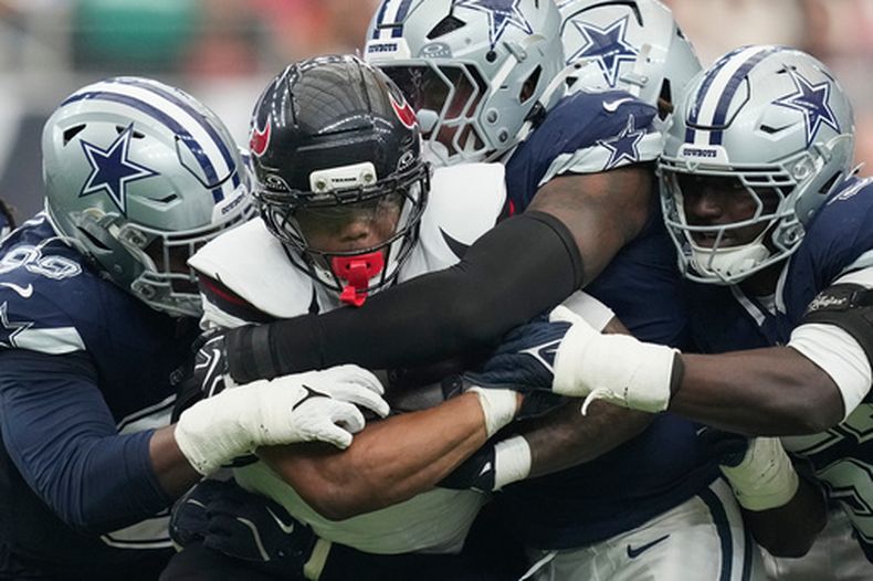 El running back David Montgomery de los Texans de Houston es derribado por los defensores de los Cowboys de Dallas, el domingo 4 de octubre de 2026, en Houston. (AP Foto/Ashley Landis)
