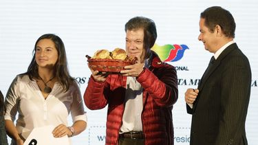 americateve | El presidente colombiano Juan Manuel Santos muestra una canasta con pan que le regal&oacute; una simpatizante, izquierda, durante un mitin de campa&ntilde;a en Soacha, en las afueras de Bogot&aacute;, Colombia, el lunes 12 de mayo de 2014. A la derecha es