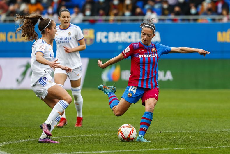 En esta foto del 13 de marzo de 2022, Aitana Bonmatí del Barcelona remata ante Maite Oroz del Real Madrid en un partido de la liga femenina de España. (AP Foto/Joan Monfort)