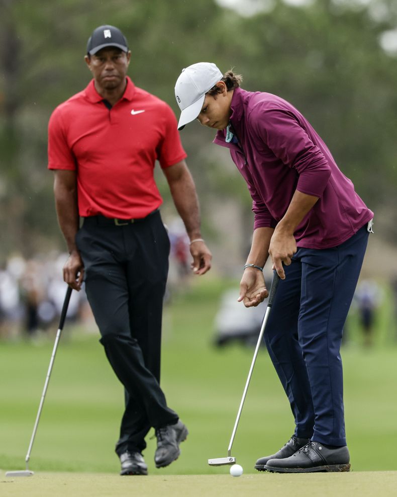 ARCHIVO - Tiger Woods, izquierda, observa a su hijo Charlie hacer un tiro desde el green, un putter durante la última ronda del torneo de golf Campeonato PNC, el domingo 17 de diciembre de 2023, en Orlando, Florida. El jueves 22 de febrero del 2024, Charlie Woods, 15, tendrá que esperar para jugar en la PGA tras una ronda de 86 en el pre clasificatorio el jueves en Hobe Sound, Florida. (AP Foto/Kevin Kolczynski, Archivo)