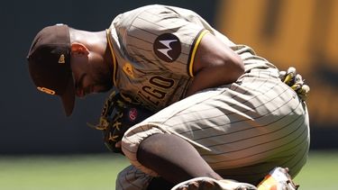 El segunda base de los Padres de San Diego, Xander Bogaerts (2), se arrodilla después de una lesión al fildear una pelota bateada por Ronald Acuña Jr., de los Bravos de Atlanta, en la tercera entrada de un juego de béisbol, el lunes 20 de mayo de 2024, en Atlanta. (AP Foto/Mike Stewart)
