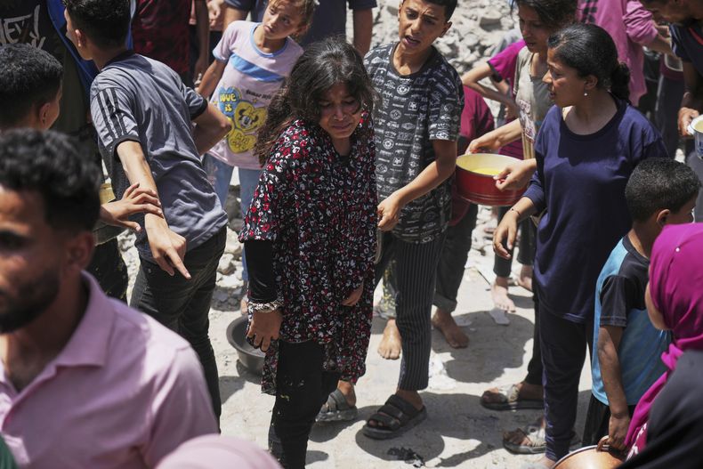 Palestinos hacen fila para conseguir comida donada en una cocina comunitaria en Jabalia, en el norte de la Franja de Gaza, el lunes 19 de mayo de 2025. (AP Foto/Jehad Alshrafi)