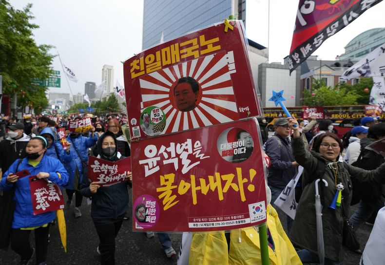 Numerosos manifestantes cargan un cartel con la imagen del presidente surcoreano Yoon Suk Yeool proyectada en una antigua bandera imperial del ejército japonés, durante una protesta contra las políticas del gobierno japonés, efectuada en Seúl, Corea del Sur, el sábado 6 de mayo de 2023. El cartel dice Traidor projaponés. (AP Foto/Ahn Young-joon)