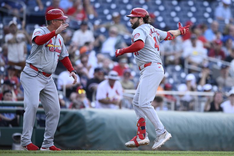 Alec Burleson, derecha, de los Cardenales de San Luis celebra después de batear un jonrón con el coach de tercera base, Ron Pop Warner, izquierda, durante la octava entrada del juego de béisbol contra los Nacionales de Washington, el lunes 8 de julio de 2024, en Washington. (AP Foto/Nick Wass)