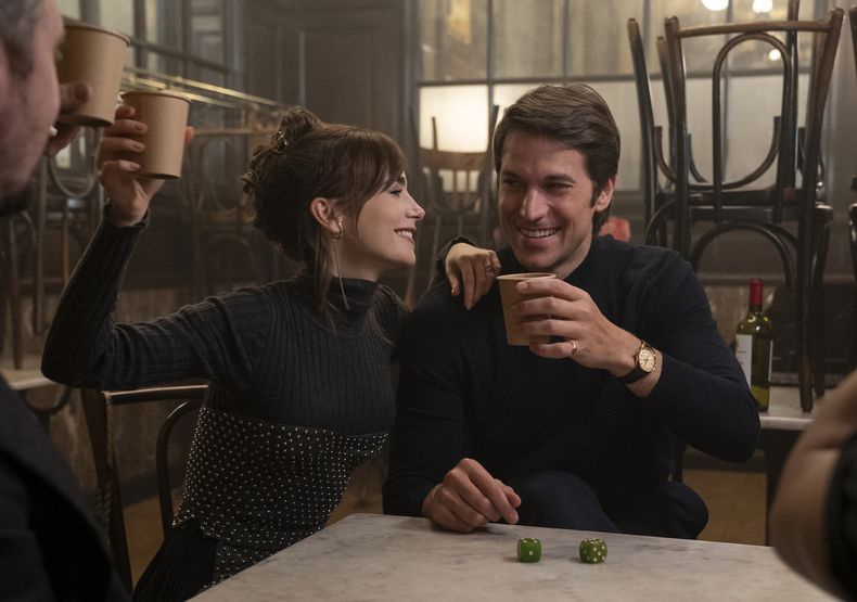 En esta imagen proporcionada por Netflix, Lily Collins, izquierda, y Lucas Bravo en una escena de Emily in Paris. (Stephanie Branchu/Netflix vía AP)