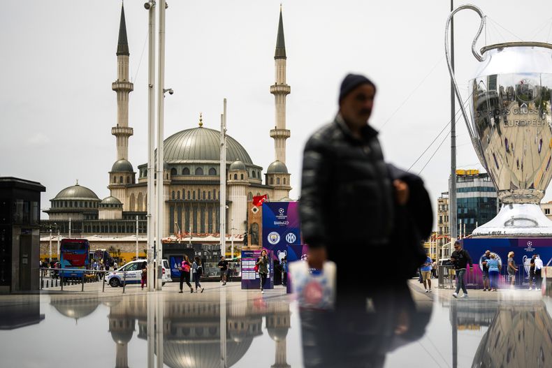Peatones caminan a un costado de un enorme trofeo de la Liga de Campeones en Taksim square, en Estambul, el jueves 8 de junio de 2023. Manchester City jugará contra Inter de Milán la final de la Liga de Campeones el sábado 10 de junio en Estambul. (AP Foto/Francisco Seco)