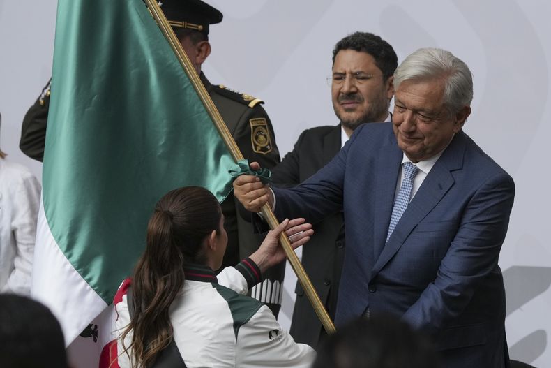 El presidente de México, Andrés Manuel López Obrador, abandera a la clavadista Alejandra Orozco, como representante de la delegación que acudirá a los Juegos Olímpicos de París, durante una ceremonia realizada el martes 11 de junio de 2024 en la capital mexicana (AP Foto/Marco Ugarte)