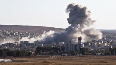 americateve | La bandera turca ondea en un almacen detr&aacute;s del que aparece humo, en la ciudad siria de Kobani, tras un ataque a&eacute;reo de la coalici&oacute;n liderada por Estados Unidos, visto desde una colina en las afueras de Suruc, en el lado turco de la f