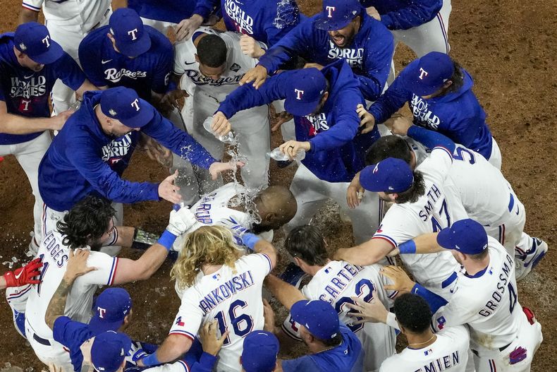 Adolis García, de los Rangers de Texas, celebra con sus compañeros de equipo después de batear el cuadrangular de la victoria sobre los Diamondbacks de Arizona en la 11ma entrada del Juego 1 de la Serie Mundial, el viernes 27 de octubre de 2023, en Arlington, Texas. Los Rangers ganaron 6-5. (AP Foto/Godofredo A. Vásquez)