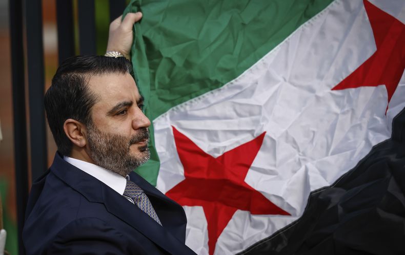 El ministro de Relaciones Exteriores de Siria, Asaad Al-Shibani, sostiene la bandera de su país en una ceremonia donde se añadió a las 100 banderas que ondean alineadas en las oficinas de Naciones Unidas, el viernes 25 de abril de 2025. (AP Foto/Kena Betancur)