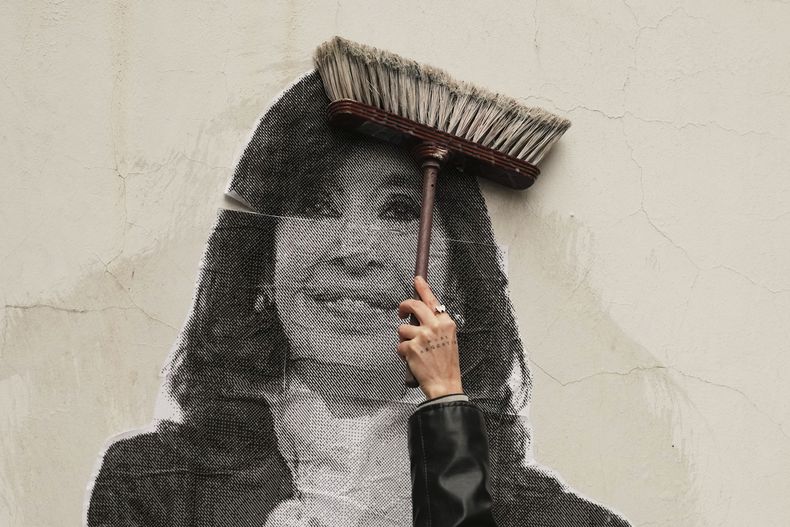 Un partidario de la expresidenta Cristina Fernández utiliza una escoba para pegar un cartel con su rostro en una pared en el exterior de su vivienda, luego de que la Corte Suprema ratificó su condena por corrupción, en Buenos Aires, Argentina, el 17 de junio de 2025. (AP Foto/Natacha Pisarenko)