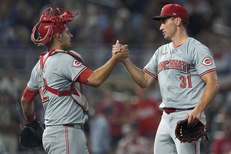 El receptor de los Rojos de Cincinnati Luke Maile (22) y el lanzador relevista Brent Suter (31) se dan la mano después de la victoria por 11-1 contra los Mellizos de Minnesota el sábado 14 de septiembre de 2024 en Minneapolis. (AP Foto/Abbie Parr)