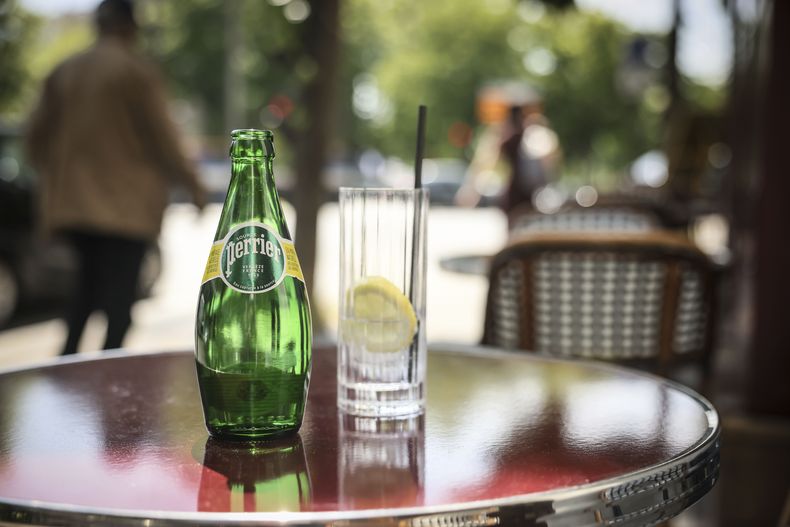 Una botella de agua Perrier en un café, en momentos en que una comisión senatorial francesa dice que el gobierno del presidente Emmanuel Macron encubrió decisiones sobre el tratamiento ilegal de agua mineral por parte de la compañía Nestle, en París, el 19 de mayo del 2025. (AP foto/Thomas Padilla)