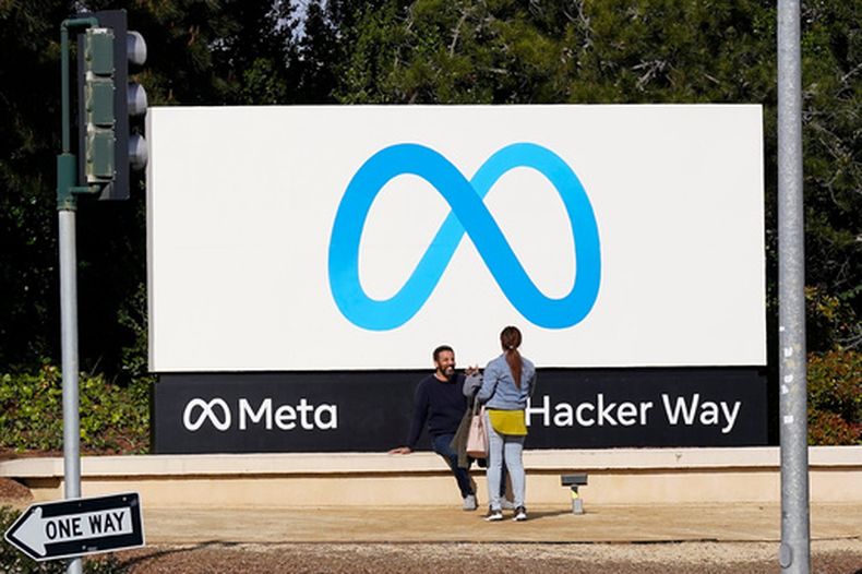 ARCHIVO – Dos personas hablan cerca de un anuncio de Meta fuera de las oficinas generales de la empresa, en Menlo Park, California, el 7 de marzo de 2023. (AP Foto/Jeff Chiu, Archivo)