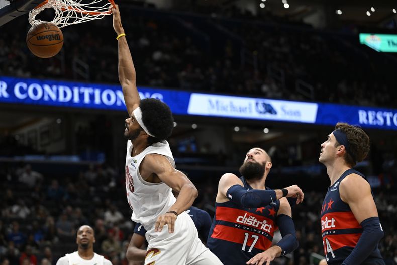 El pívot de los Cavaliers de Cleveland Jarrett Allen clava el balón frente al pívot Jonas Valanciunas y el alero Corey Kispert de los Wizards de Washington el sábado 26 de octubre del 2024. (AP Foto/John McDonnell)