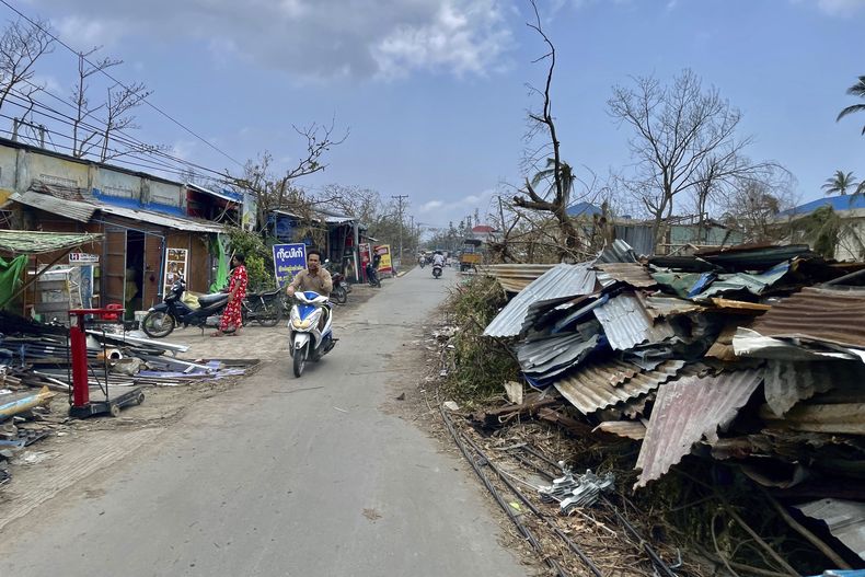 Una persona circula en un ciclomotor por una calle con edificios dañados por el paso del ciclón Mocha, en la localidad de Sittwe, en el estado de Rakhine, Myanmar, el 19 de mayo de 2023. (AP Foto)