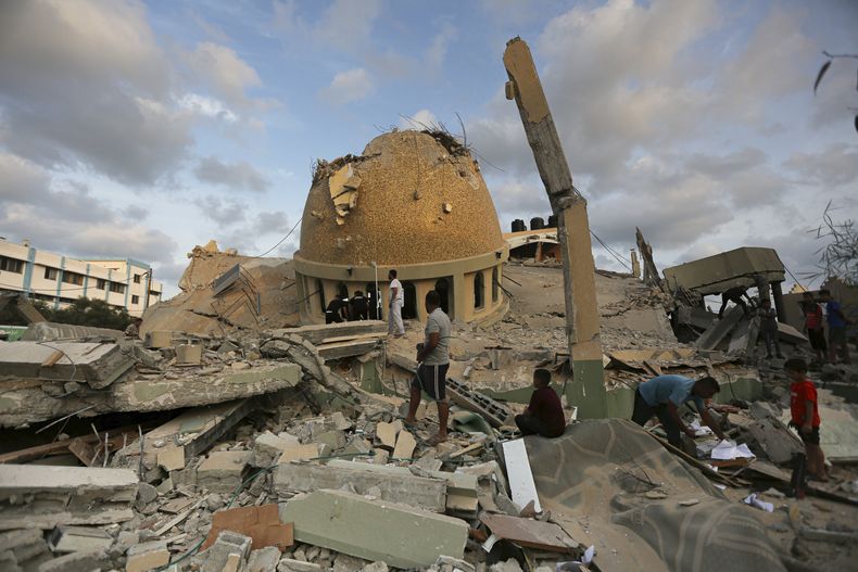 Varias personas examinan las ruinas de una mezquita destruida por un ataque aéreo israelí, el domingo 8 de octubre de 2023, en Khan Younis, Franja de Gaza. (AP Foto/Yousef Masoud)
