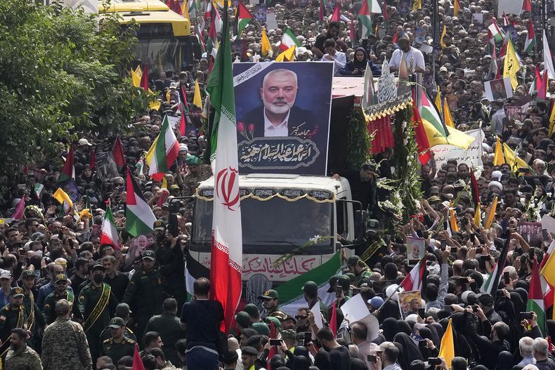 Iraníes siguen el jueves 1 de agosto de 2024 un camión que lleva los ataúdes del dirigente político de Hamás, Ismail Haniyeh, y su guardaespaldas, que fueron asesinados en un ataque que ha sido atribuido a Israel y que fue perpetrado en la víspera, durante su funeral en Teherán, Irán. (AP Foto/Vahid Salemi)