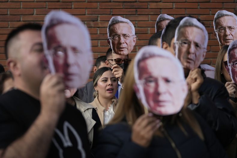 Partidarios del expresidente colombiano Álvaro Uribe sostienen recortes de su retrato afuera del tribunal donde asiste a una audiencia por presuntos cargos de manipulación de testigos y soborno en Bogotá, Colombia, el lunes 10 de febrero de 2025. (Foto AP/Fernando Vergara)