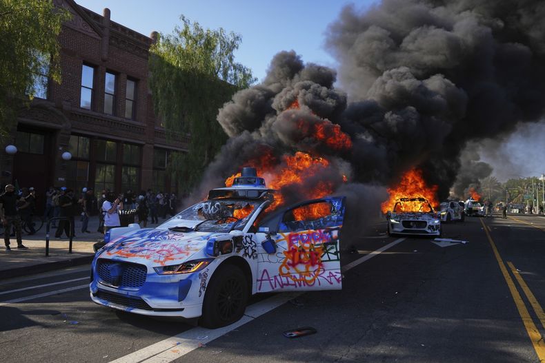 Varios taxis de Waymo arden cerca del Centro Metropolitano de Detención en el centro de Los Ángeles, el domingo 8 de junio de 2025, tras la protesta del día anterior contra las redadas migratorias. (AP Foto/Eric Thayer)