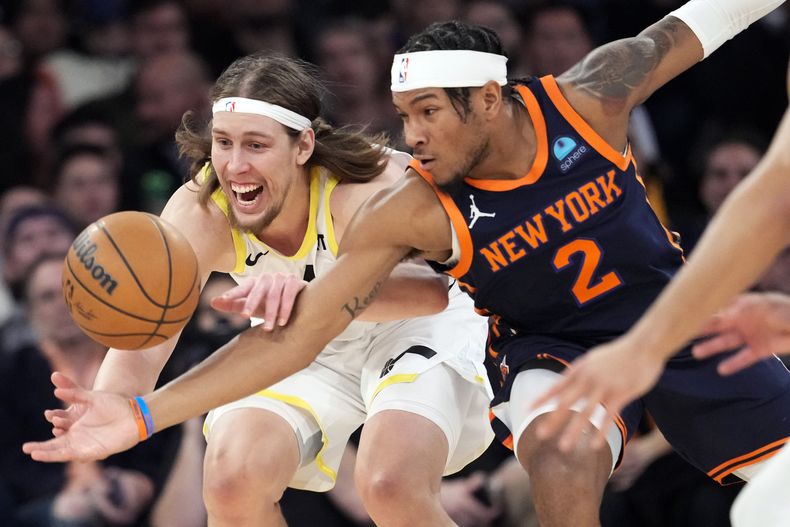 El alero del Jazz de Utah Kelly Olynyk y el escolta de los Knicks de Nueva York Miles McBride (2) persiguen un balón suelto durante la segunda mitad del partido de baloncesto de la NBA, el martes 30 de enero de 2024, en el Madison Square Garden de Nueva York. Los Knicks ganaron 118-103. (AP Foto/Mary Altaffer)