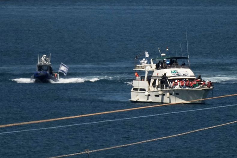 Activistas con chalecos salvavidas color anaranjado a bordo de un barco de la Flotilla Sumud con destino a Gaza mientras soldados de la Armada de Israel lo escoltan a puerto, el 2 de octubre de 2025, en Ashdod, Israel, después de interceptar a la embarcación mientras se acercaba a la costa de Gaza. (AP Foto/Leo Correa, Archivo)