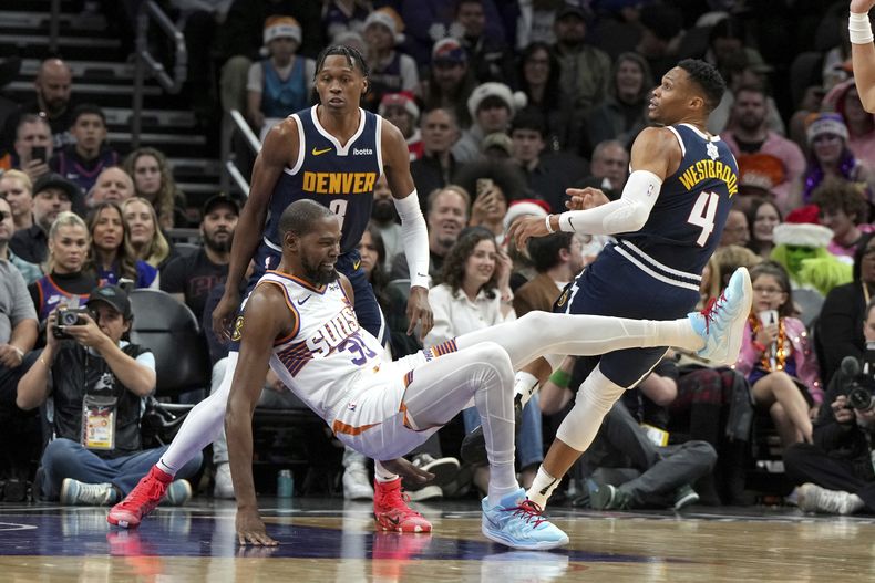 Kevin Durant, alero de los Suns de Phoenix, cae tras recibir una falta de Russell Westbrook, de los Nuggets de Denver, el miércoles 25 de diciembre de 2024 (AP Foto/Rick Scuteri)