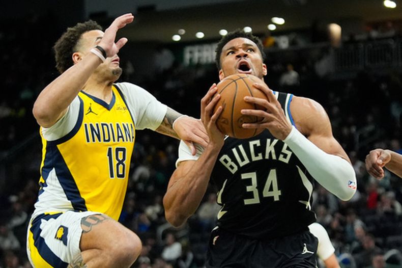El pívot de los Bucks de Milwaukee, Giannis Antetokounmpo (34), penetra hacia la canasta ante Jalen Slawson (18), de los Pacers de Indiana, durante la segunda mitad de un juego de baloncesto de la NBA, el domingo 15 de marzo de 2026, en Milwaukee. (Foto AP/Aaron Gash)