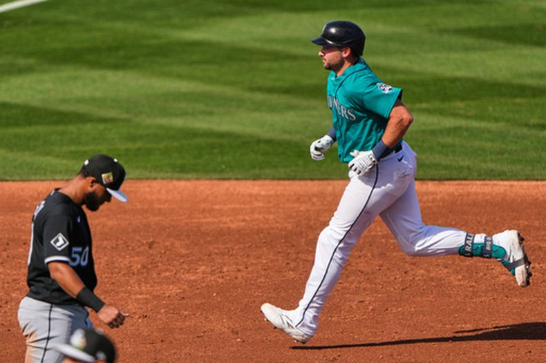 El receptor de los Marineros de Seattle, Cal Raleigh, recorre las bases ante el tercera base de los Medias Blancas de Chicago, Lenyn Sosa, tras conectar un jonrón de dos carreras durante la tercera entrada de un juego de béisbol de pretemporada el martes 24 de febrero de 2026, en Peoria, Arizona. (Foto AP/Charlie Riedel)