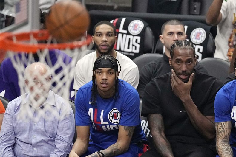 Kawhi Leonard (derecha), de los Clippers de Los Ángeles, observa desde la banca el cuarto partido de la serie de playoffs ante los Suns de Phoenix, el sábado 22 de abril de 2023 (AP Foto/Mark J. Terrill)