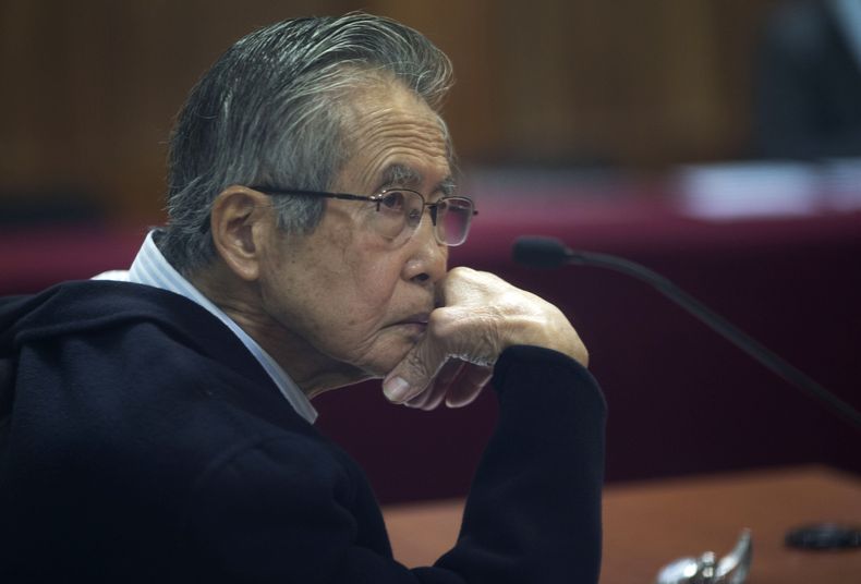 ARCHIVO - El encarcelado expresidente peruano Alberto Fujimori, fotografiado a través de una ventana de vidrio, asiste a su juicio en una base policial en las afueras de Lima, Perú, el 28 de junio de 2016. La agencia carcelaria de Perú dijo el lunes 7 de agosto de 2023 que Fujimori salió de prisión para ir al dentista tras la difusión de un video donde se lo ve bajar de una ambulancia y e ingresar caminando sin grilletes a un centro de belleza. (AP Foto/Martín Mejía, Archivo)