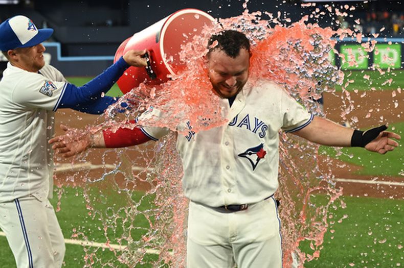 El jardinero Myles Straw, izquierda, de los Azulejos de Toronto, baña al receptor Alejandro Kirk para celebrar la victoria del equipo sobre los Astros de Houston en el juego de béisbol de Grandes Ligas, el lunes 22 de junio de 2026, en Toronto. (Jon Blacker/The Canadian Press via AP)