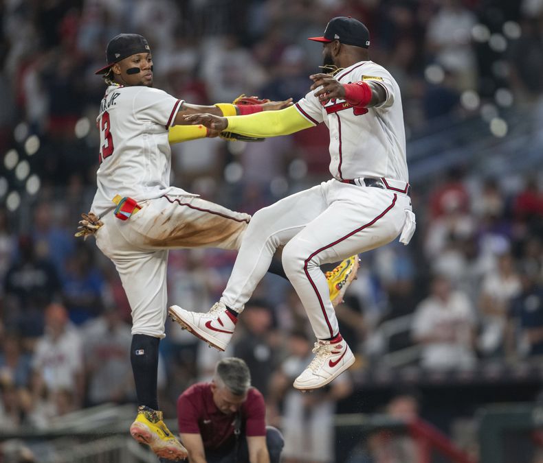 El venezolano Ronald Acuña Jr. y el dominicano Marcell Ozuna festejan la victoria de los Bravos de Atlanta sobre los Mets de Nueva York, el miércoles 23 de agosto de 2023 (AP Foto/Hakim Wright Sr.)
