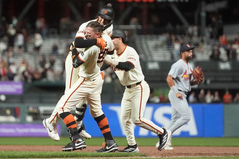 Shay Whitcomb, arriba, de los Gigantes de San Francisco, es felicitado por Christian Koss, abajo, y Nate Furman, derecha, después de que bateara el sencillo productor decisivo en la 11ma entrada del juego de béisbol de Grandes Ligas contra los Cardenales de San Luis, el lunes 7 de septiembre de 2026, en San Francisco. (AP Foto/Jeff Chiu)