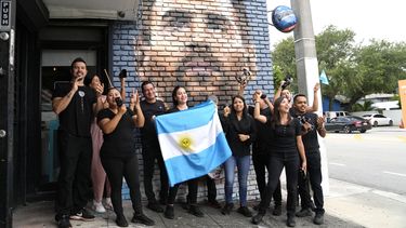 Personal del restaurante Fiorito porta una bandera de Argentina frente a un mural de Lionel Messi en Miami, el miércoles 7 de junio de 2023. (AP Foto/Lynne Sladky)