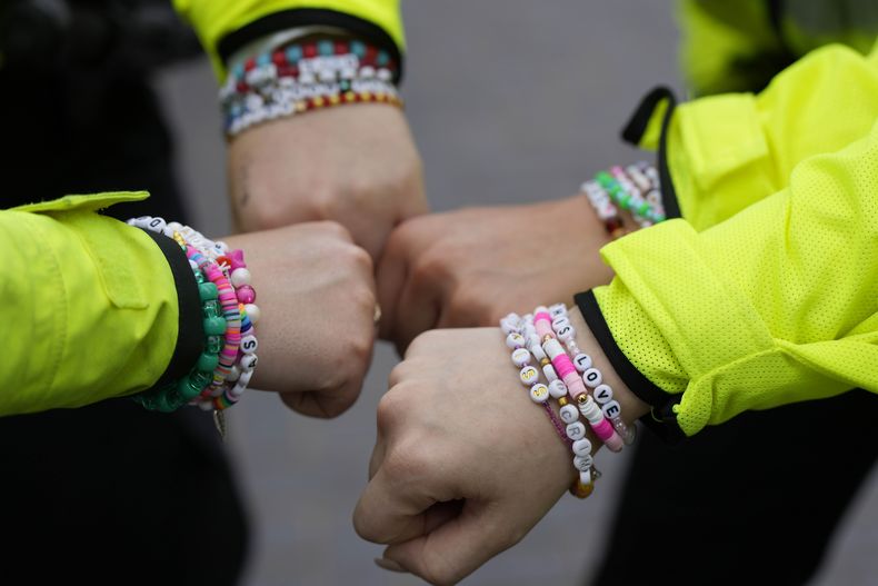 Cuatro policías muestran sus brazaletes de la amistad previo a un concierto de Taylor Swift en el Wembley Stadium en Londres, el jueves 15 de agosto de 2024 para el primero de cinco conciertos de la gira Eras de Swift. (Foto AP/Alastair Grant)