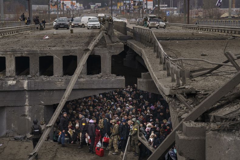 Ucranianos se amontonan bajo un puente destruido mientras intentan huir cruzando el río Irpin en las afueras de Kiev, Ucrania, el sábado 5 de marzo de 2022. (AP Foto/ Emilio Morenatti)