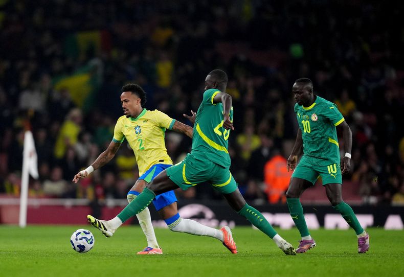 Éder Militão, de Brasil, a la izquierda, y Pape Gueye, de Senegal, luchan por el balón durante un juego internacional de fútbol entre Brasil y Senegal en el Emirates Stadium, Londres, el sábado 15 de noviembre de 2025. (John Walton/PA vía AP)