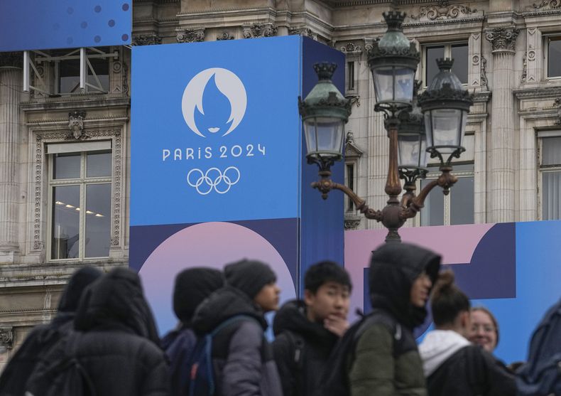 Un grupo de jóvenes frente al Ayuntamiento de París y el logo de los Juegos Olímpicos de París 2024, el martes 5 de marzo de 2024. (AP Foto/Michel Euler)