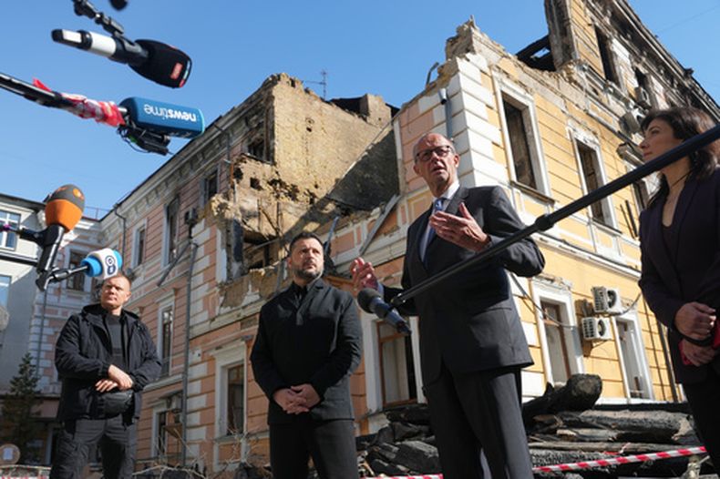 El presidente de Ucrania, Volodymyr Zelenskyy, en el centro, y el canciller alemán, Friedrich Merz, hablan a los medios junto al edificio de la Academia Nacional de Ciencias, dañado por un ataque de dron ruso, en Kiev, Ucrania, el domingo 4 de octubre de 2026. (AP Foto/Evgeniy Maloletka)