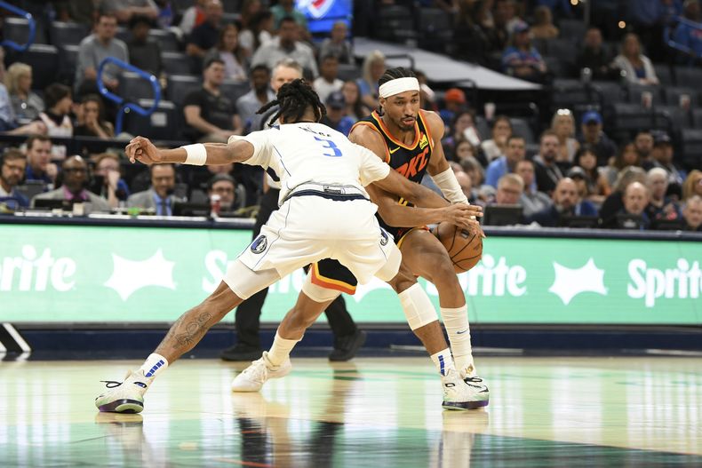 Aaron Wiggins, derecha, del Thunder de Oklahoma City, lleva el balón y busca a quien pasarlo, mientras Alex Fudge (3) de los Mavericks de Dallas, presiona durante la segunda mitad del juego de baloncesto de la NBA, el domingo 14 de abril de 2024, en Oklahoma City. (AP Foto/Kyle Phillips)
