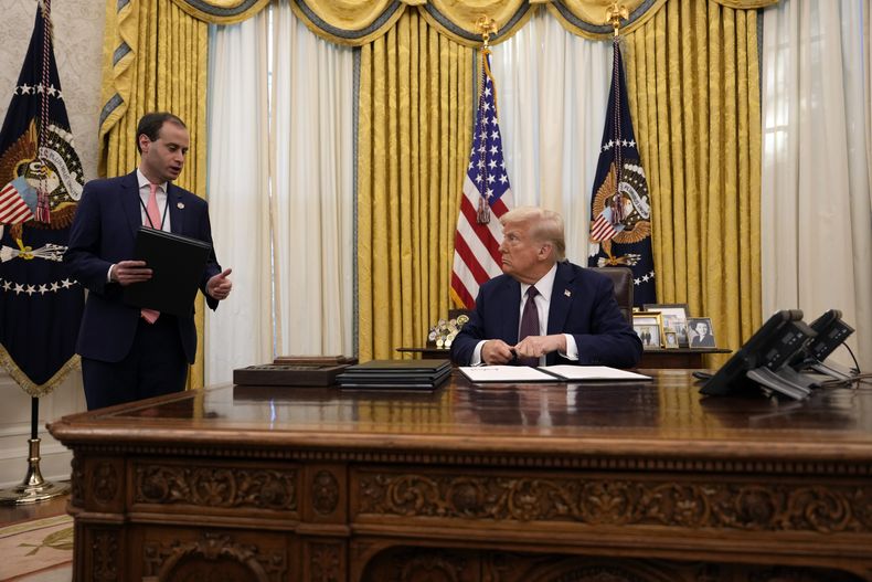 El presidente Donald Trump habla con Will Scharf, secretario de personal de la Casa Blanca, mientras firma órdenes ejecutivas en la Oficina Oval de la Casa Blanca, el jueves 23 de enero de 2025, en Washington. (AP Foto/Ben Curtis)