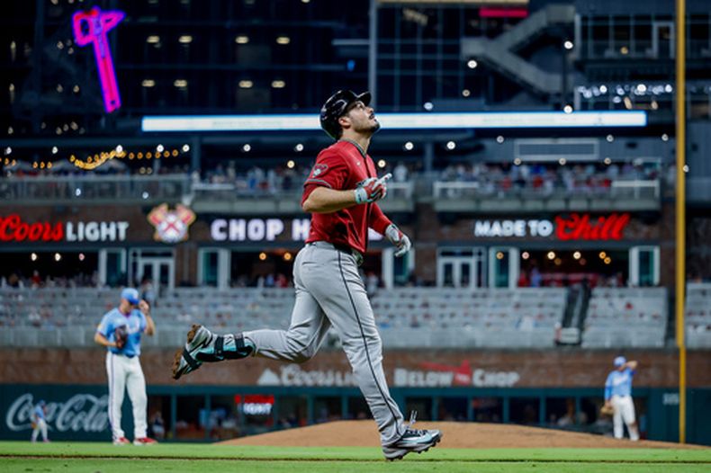 Nolan Arenado, de los Diamondbacks de Arizona, (derecha) reacciona mientras corre las bases, tras conectarle un jonrón al pitcher Brent Suter, de los Bravos de Atlenta, (izquierda) durante la séptima entrada un juego de béisbol, sábado 15 de agosto de 2026, en Atlanta. (AP Photo/Erik S. Lesser)